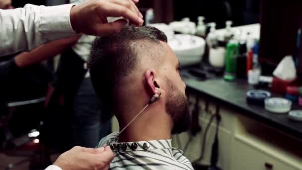 Hipster man client een bezoek aan haidresser en hairstylist in kapper, oor ontharing. — Stockvideo