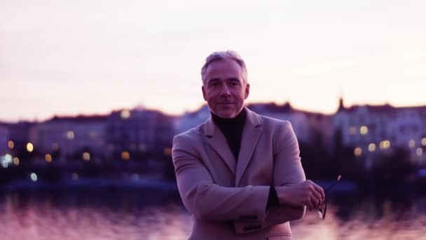 Зрелый бизнесмен стоит на мосту в Праге в сумерках . — стоковое видео