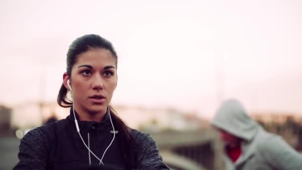Fit pár běžců dělá cvičení venku na mostě v Praze. — Stock video