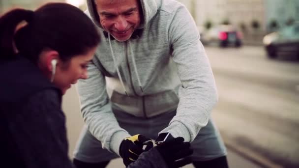 Підходить пара бігунів, що вимірюють час на вулиці на вулиці міста . — стокове відео