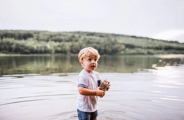 Ein nasser kleiner Junge, der im Sommer draußen in einem Fluss steht und spielt. — Stockfoto