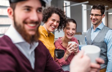 Genç iş adamları bir grup fincan kahve ayakta Office ile.