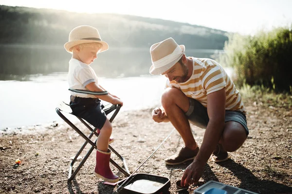 Взрослый отец с маленьким ребенком на открытом воздухе рыбачит у озера, разговаривает . — стоковое фото