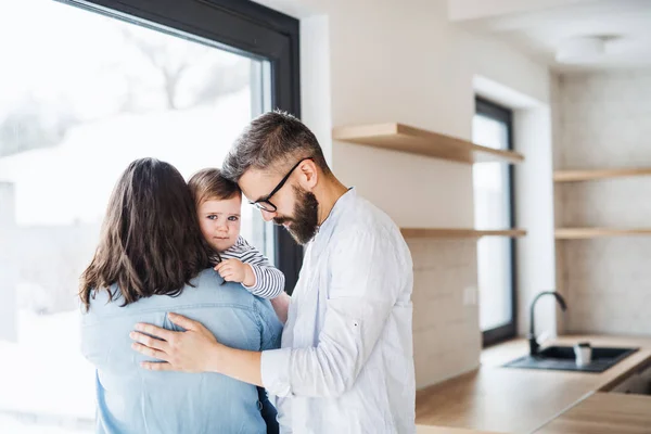 A young family with a toddler girl standing indoors at home. — Stock Photo, Image