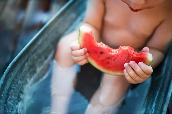 Egy kisfiú kint a kertben, a nyári fürdő enni görögdinnye, midsection. — Stock Fotó