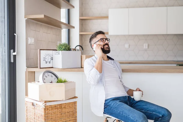 Un homme mature avec smartphone déménageant dans une nouvelle maison, passer un appel téléphonique . — Photo