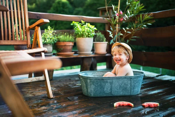 Kleiner Junge mit Hut und Wassermelone im Freibad im Sommer im Garten. — Stockfoto