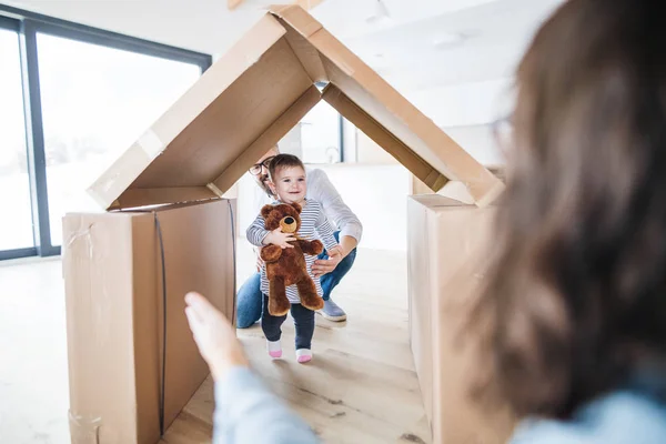 Sebuah keluarga muda dengan seorang gadis balita di dalam ruangan, bergerak dalam konsep rumah baru . — Stok Foto