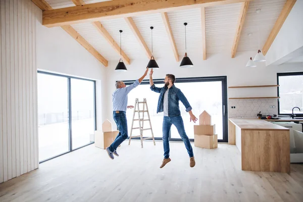 Un homme mûr sautant avec son père aîné dans une nouvelle maison, un nouveau concept de maison . — Photo