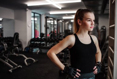 Genç kız ya da bir spor salonunda duran kadın portresi eller kalçalarına.