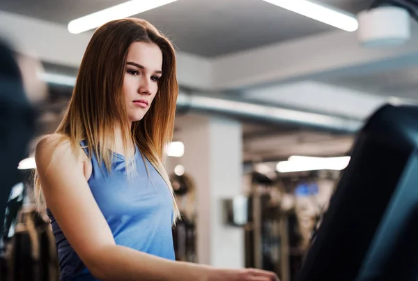 A portrait of young girl or woman doing cardio workout in a gym. — Stock Photo, Image