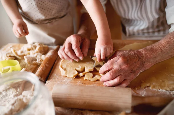 Sección media de la abuela con un niño pequeño haciendo pasteles en casa . —  Fotos de Stock