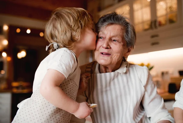 Старша бабуся з маленьким хлопчиком робить торти вдома, цілує . — стокове фото