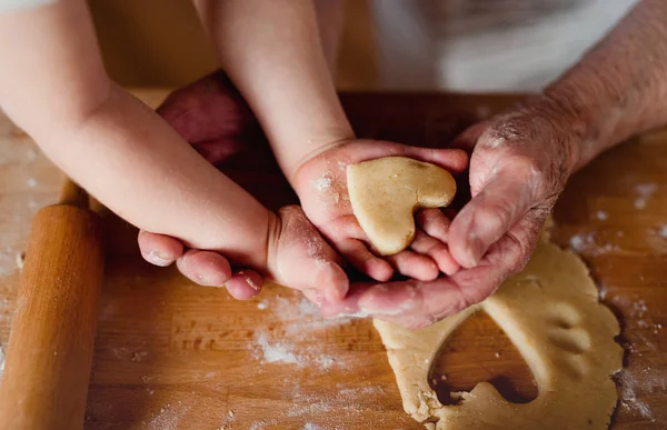 Sección media de la abuela con un niño pequeño haciendo pasteles en casa . —  Fotos de Stock