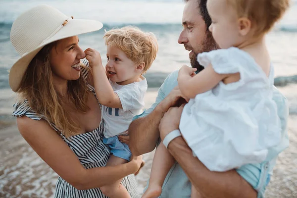 Una giovane famiglia con due bambini piccoli in spiaggia in vacanza estiva . — Foto Stock