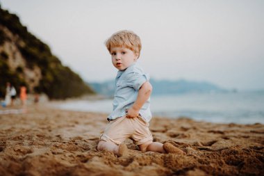Oynarken yaz tatilde plajda küçük yürümeye başlayan çocuk.