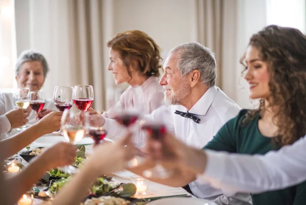 Uma grande família sentada em uma mesa em uma festa de aniversário indoor, óculos de claque . — Fotografia de Stock