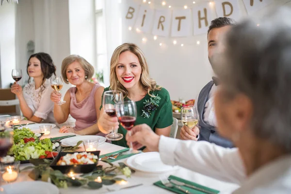 Una gran familia sentada en una mesa en una fiesta de cumpleaños cubierta, gafas de tintineo . —  Fotos de Stock
