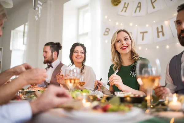 Una gran familia sentada en una mesa en una fiesta de cumpleaños cubierta, comiendo . —  Fotos de Stock