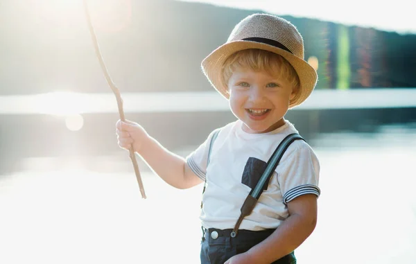 A small toddler boy standing by a lake at sunset. Copy space. — Stock Photo, Image