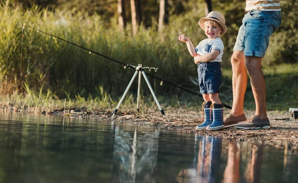 Otec se synem malé batole venku rybaření u jezera. — Stock fotografie