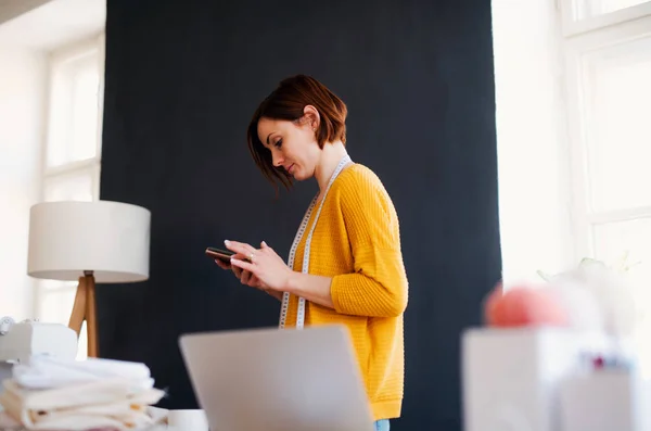 Giovane donna creativa in uno studio, utilizzando smartphone. Una startup di sartoria aziendale . — Foto Stock