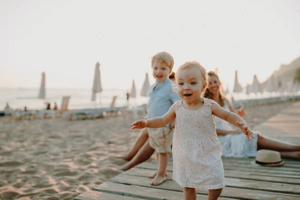 Familia joven con niños pequeños divirtiéndose en la playa en vacaciones de verano . —  Fotos de Stock