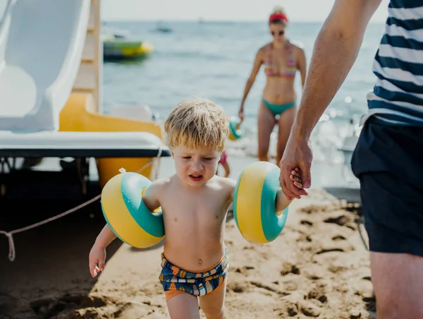 Familia con dos niños pequeños caminando en la playa en vacaciones de verano . —  Fotos de Stock