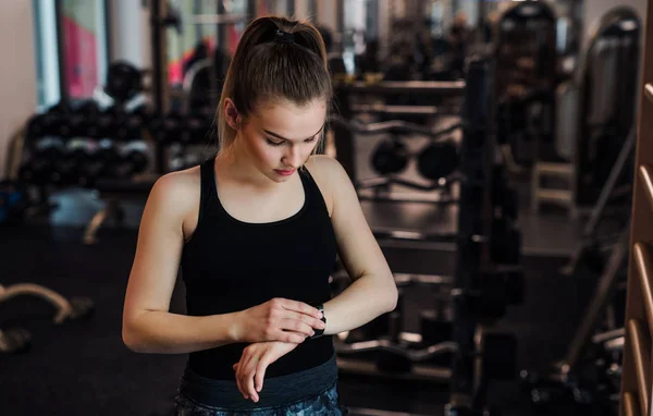 Genç kız ya da bir spor salonunda egzersiz yapıyor kadın smartwatch kullanarak. — Stok fotoğraf