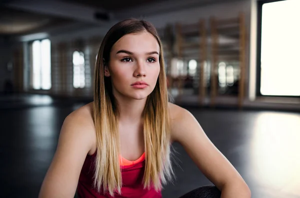 A portrait of young sad girl or woman sitting in a gym. — Stock Photo, Image