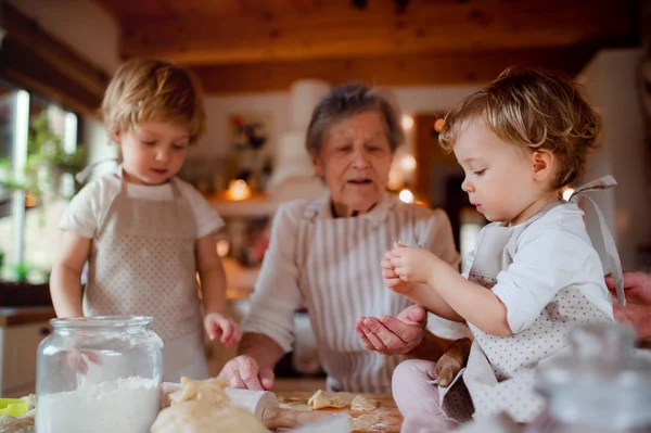 Grand-mère aînée avec des enfants en bas âge faisant des gâteaux à la maison . — Photo