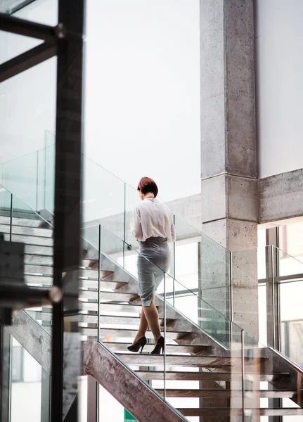 Uma visão traseira da jovem empresária subindo as escadas no prédio de escritórios . — Fotografia de Stock