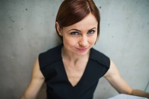 Porträt einer jungen Geschäftsfrau, die im Büro steht und in die Kamera blickt. — Stockfoto