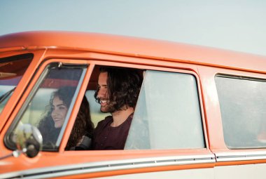 A young couple on a roadtrip through countryside, driving minivan. clipart