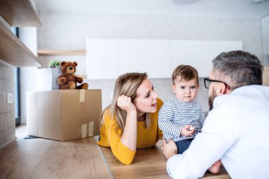 Yeni evinde hareketli bir yürümeye başlayan çocuk kızla genç aile portresi.