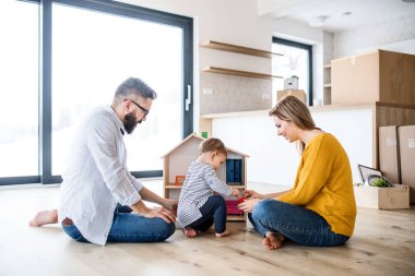 Yeni ev taşıma, oynarken bir yürümeye başlayan çocuk kızla genç aile portresi.