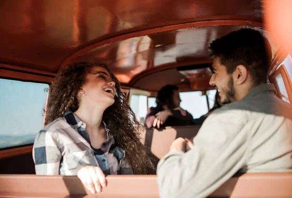 Een groep jonge vrienden op een roadtrip door het platteland, zittend in een minibus. — Stockfoto