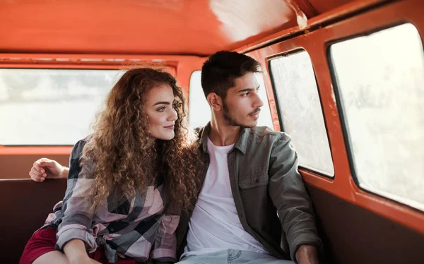 Um jovem casal em uma viagem pelo campo, sentado em minivan . — Fotografia de Stock