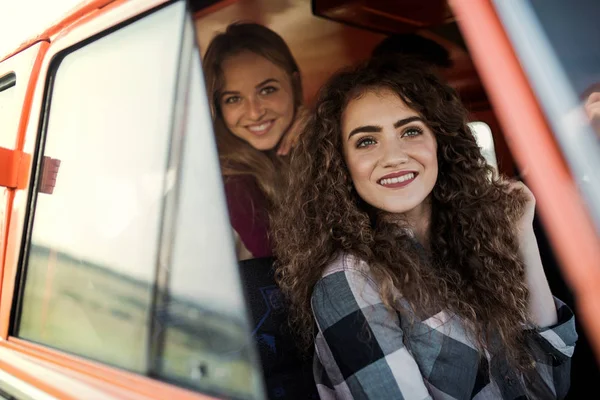 Jonge vrouwelijke vrienden op een roadtrip door het platteland, kijken uit minibus. — Stockfoto