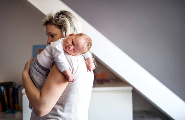 Eine schöne junge Mutter mit einem schlafenden Neugeborenen zu Hause. Kopierraum. — Stockfoto