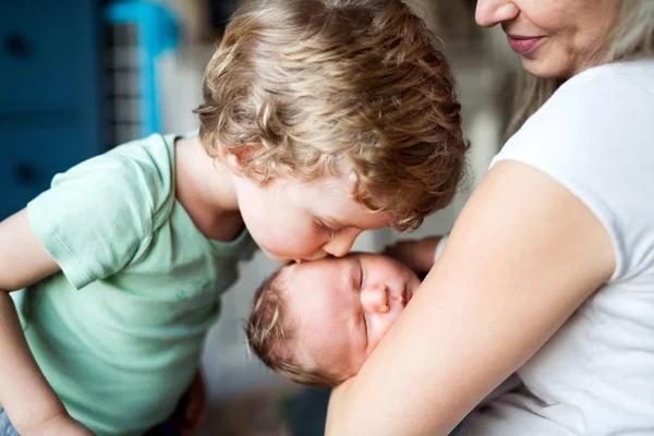 Un petit garçon embrassant un nouveau-né endormi frère à la maison . — Photo