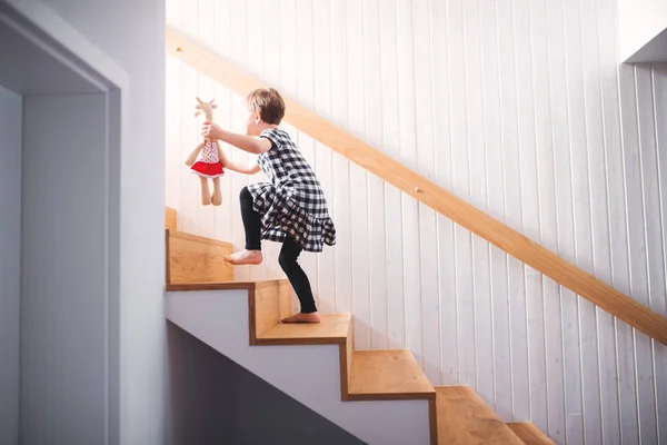 Een klein kind met een zacht stuk speelgoed lopen de trap. — Stockfoto