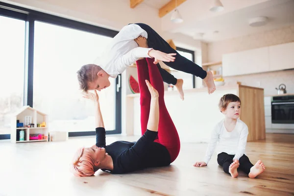 Młoda kobieta z dwóch dzieci bawiące się na podłodze, zabawy. — Zdjęcie stockowe