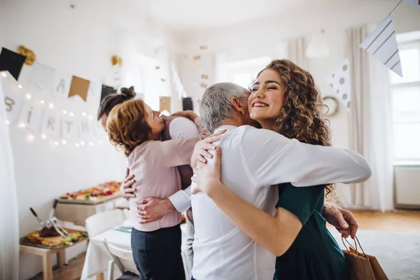 Una giovane coppia che saluta genitori o nonni alla festa di compleanno al coperto . — Foto Stock