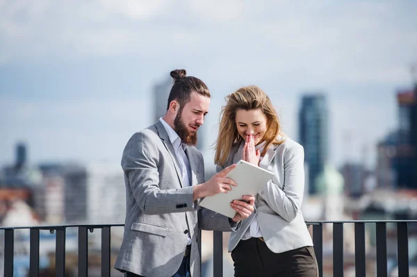 Zwei junge Geschäftsleute mit Tablet stehen auf einer Terrasse vor dem Büro und arbeiten. — Stockfoto