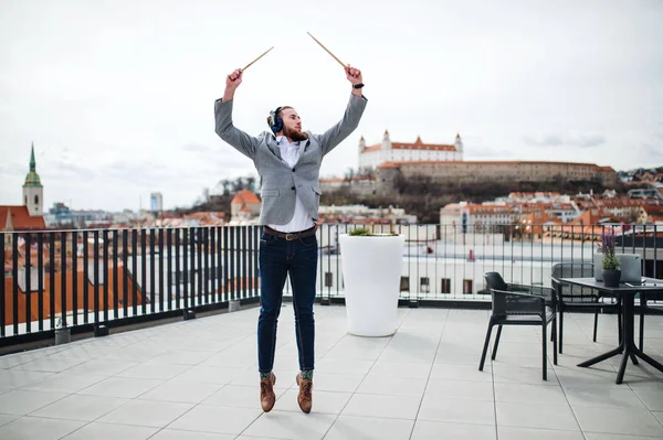 A young businessman with headphones standing on a terrace, having fun. — Stock Photo, Image