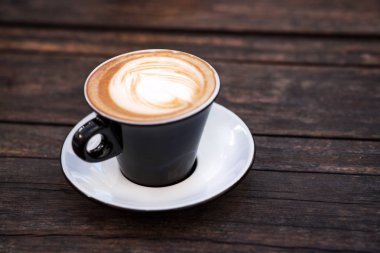 bir fincan kahve koyu ahşap bir masa üzerinde.