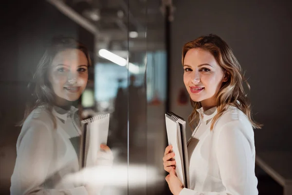 Porträt einer jungen Geschäftsfrau in einem Büro, die in die Kamera blickt. — Stockfoto