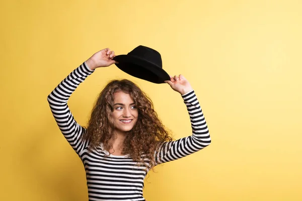 Портрет молодої жінки з чорним капелюхом в студії на жовтому тлі . — стокове фото