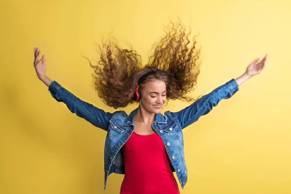 黄色の背景にスタジオでヘッドフォンと若い女性の肖像. — ストック写真